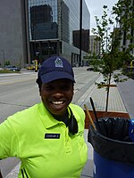 Waist high portrait of young woman wearing electric green shirt and navy blue baseball cap standing on Marquette Av downtown