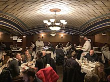 One of the remaining vaults of the Della Robbia Room's bar. The ceiling is made of white Guastavino tiles in a blue, tan, and aqua color scheme. The bar has housed Wolfgang's Steakhouse since 2004.