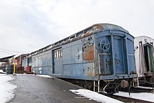 An old windowless baggage car with rusting blue paint