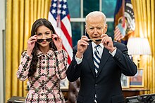 Olivia Rodrigo with the U.S. President Joe Biden at the Oval Office, posing to press cameras with sunglasses, as part of a government campaign that aims to encourage the American youth to get vaccinated against COVID-19