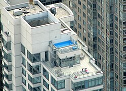 A modern, transparent parapet surrounds a New York City rooftop.