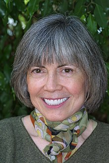 Portrait du visage d'une femme aux cheveux gris, souriante.