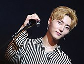 An image of Young K looking into the camera while holding a microphone
