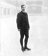 seorang pria berdiri di atas es dengan sepatu luncur