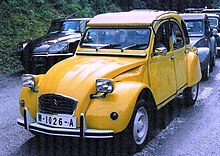 A yellow car drives down a grassy road.