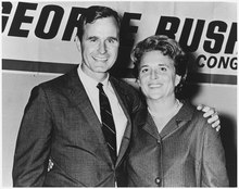 George and Barabara stand in front of a George Bush for Congress sign. George's arm is around Barbara's shoulders.