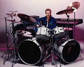 Promotional photo of John Robinson sitting behind a Yamaha drum kit in 1985