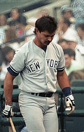 A medium-wide shot of baseball player Don Mattingly holding a bat and looking down.