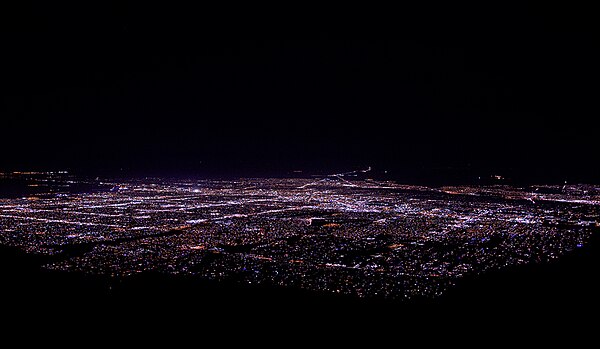 Photo shows the nighttime cityscape of Albuquerque as seen looking west by south from the upper terminal of Sandia Peak Tramway