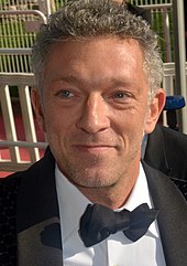 Vincent Cassel wearing a black suit and bow tie