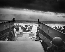 A photograph of troops disembarking into the ocean from the U.S. Coast Guard-manned USS Samuel Chase at the Fox Green section of Omaha Beach (Calvados, Basse-Normandie, France) on the morning of June 6, 1944