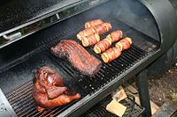 Chicken, pork and corn cooking in a barbecue smoker