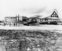 一架大型四引擎飞机停在跑道上，前面站着九名机组人员。