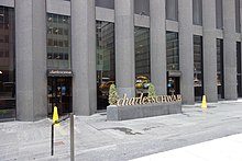 The Sixth Avenue entrances to the CBS Building, looking east. There is a small sculpted sign with Charles Schwab's logo in front of the building's entrances.