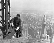 A man is working on an I-Beam while the Chrysler Building is seen in the background at right