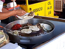 Tacos de suadero (grey) and chorizo (red) being prepared at a taco stand