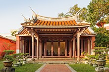 Photo of an elaborate Chinese temple with hedges in front.