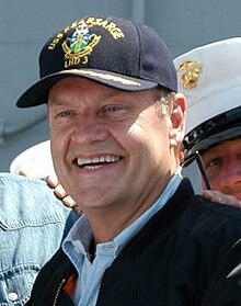 A man wearing a cap smiles broadly.