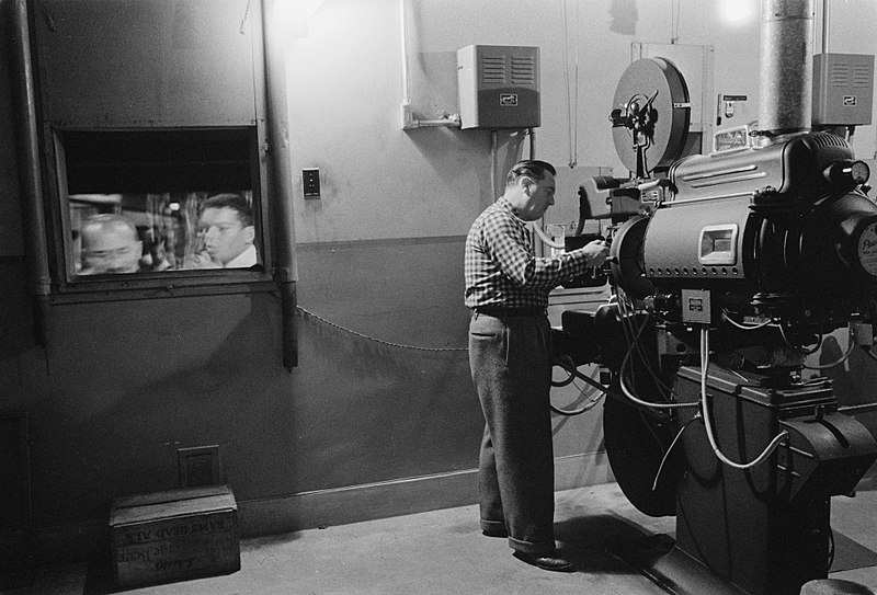 Man working with a movie projector in a movie theater, 1958