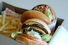 An In-N-Out "Double-Double" cheeseburger with fries in a box for consumption in a car