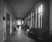 Old photograph of a hallway with people sitting