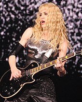 Madonna in a silver dress, playing electric guitar