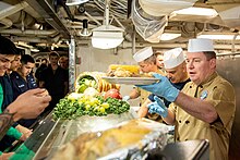 Sailors of the U.S. Navy are served Thanksgiving meals aboard the aircraft carrier USS Ronald Reagan in the Philippine Sea, November 2022.