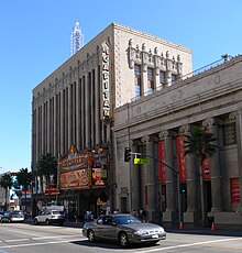 The El Capitan Theatre (a low-rise white building) as seen from Hollywood Boulevard