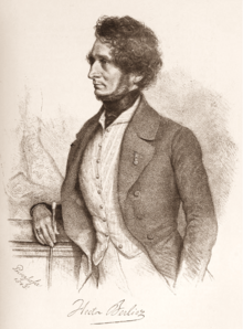 portrait of white man in early middle age, seen in left profile; he has bushy hair and a neckbeard but no moustache.