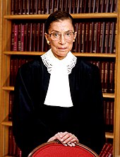 Ginsburg standing in front of a bookshelf