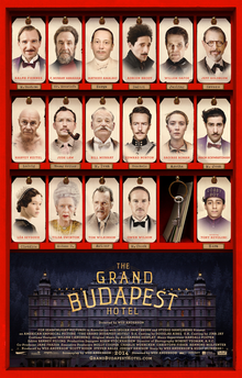 Theatrical release poster, featuring the principal cast on a key card–hotel mailroom motif. The words "The Grand Budapest Hotel" are written in the foreground, superimposed on a dusk shot of the namesake building.