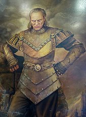 An image of Wilhelm von Homburg in character as Vigo the Carpathian. An imitation canvas painting of a middle-aged white man with shoulder-length dark blonde hair. He is scowling while looking forward. The man is shown wearing ancient armor that covers most of his body.