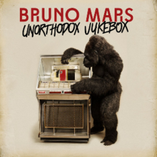 A man wearing a gorilla costume standing next to a jukebox and holding it. The words "Bruno Mars" in red capital font are above the words "Unorthodox Jukebox" with capital font, both are on the top of the image.