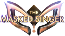 The words "The Masked Singer" in a gold-colored, capitalized typeface appearing in front of a 3D mask design