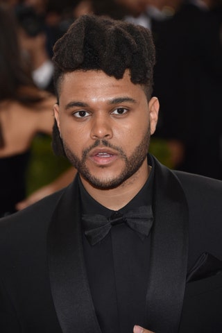 Image may contain The Weeknd Face Human Person Coat Clothing Suit Overcoat Apparel Tie Accessories and Accessory