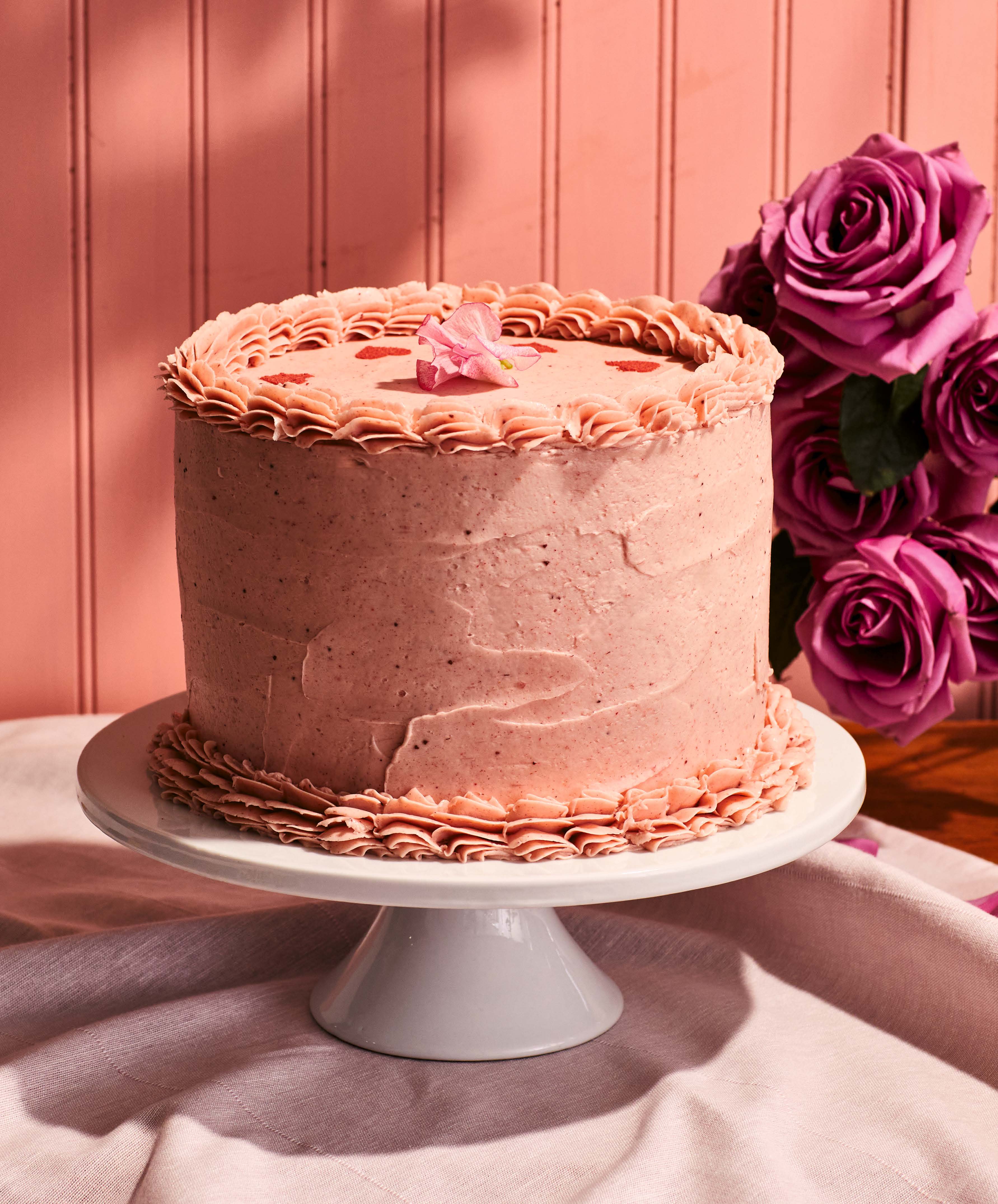 Pink frosted cake on a cake stand.
