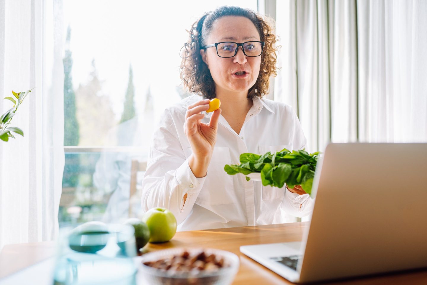 Nutritionist holds food up to her laptop screen.