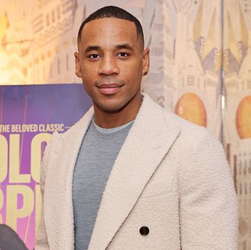 reggie yates at the color purple screening, wearing a grey jumper and a cream coat