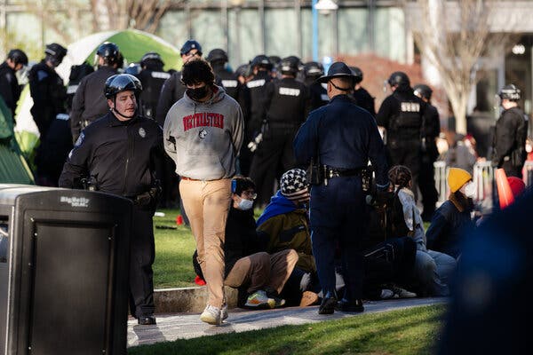 A protester is led away by a police officer at Northeastern University early Saturday morning.