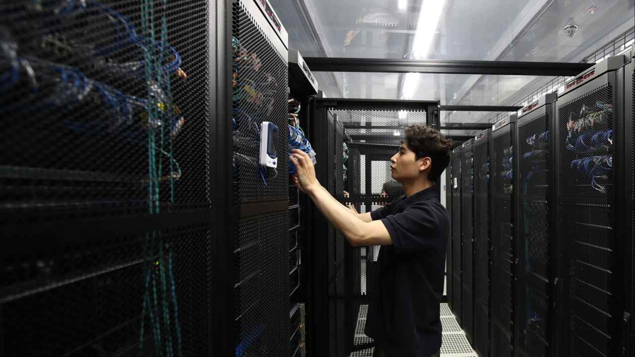 A Samsung employee wearing a black shirt checks technological equipment in a server room